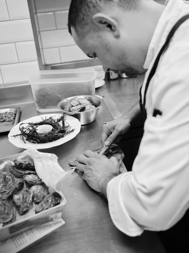 Chef maakt oesters klaar, in zwart-wit