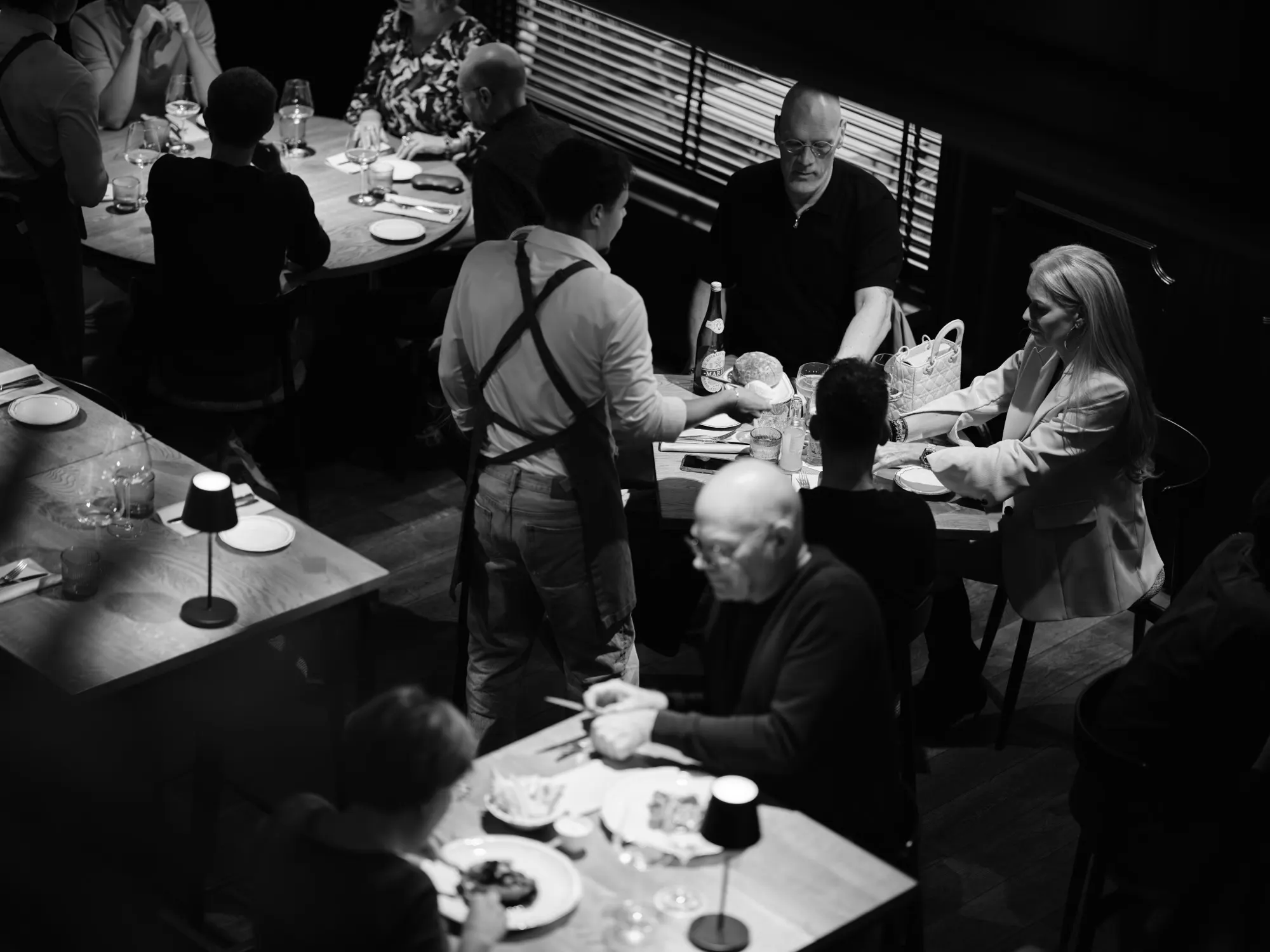 Volle zaal bij DIELS met gasten aan tafel, in zwart-wit